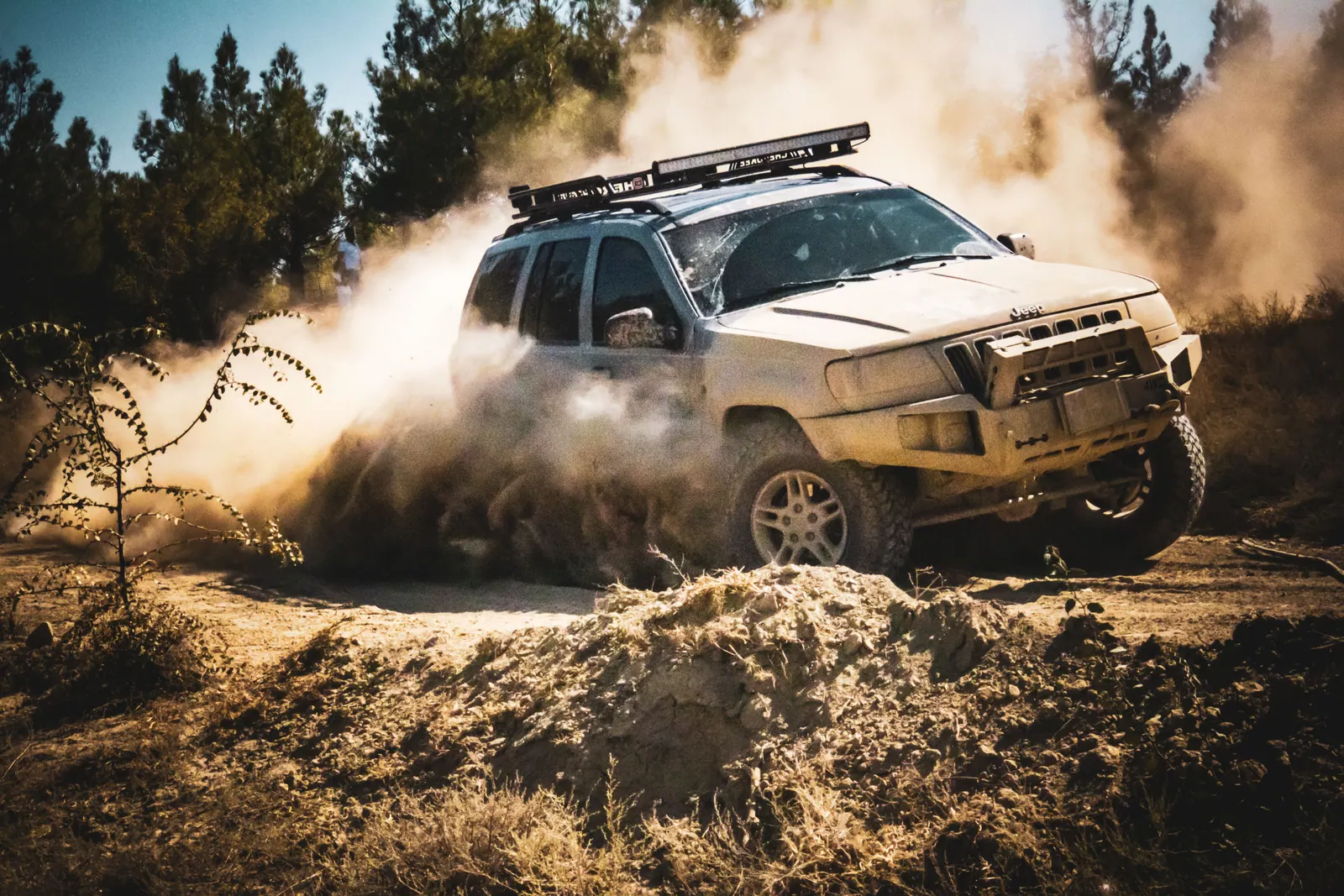 An SUV driving along a dirt road through a forest